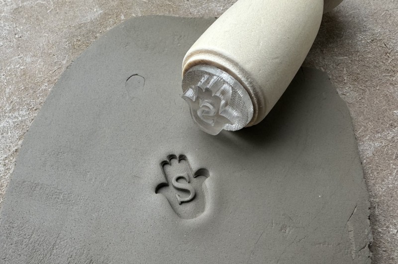 Personalized pottery stamp with letter and hand
